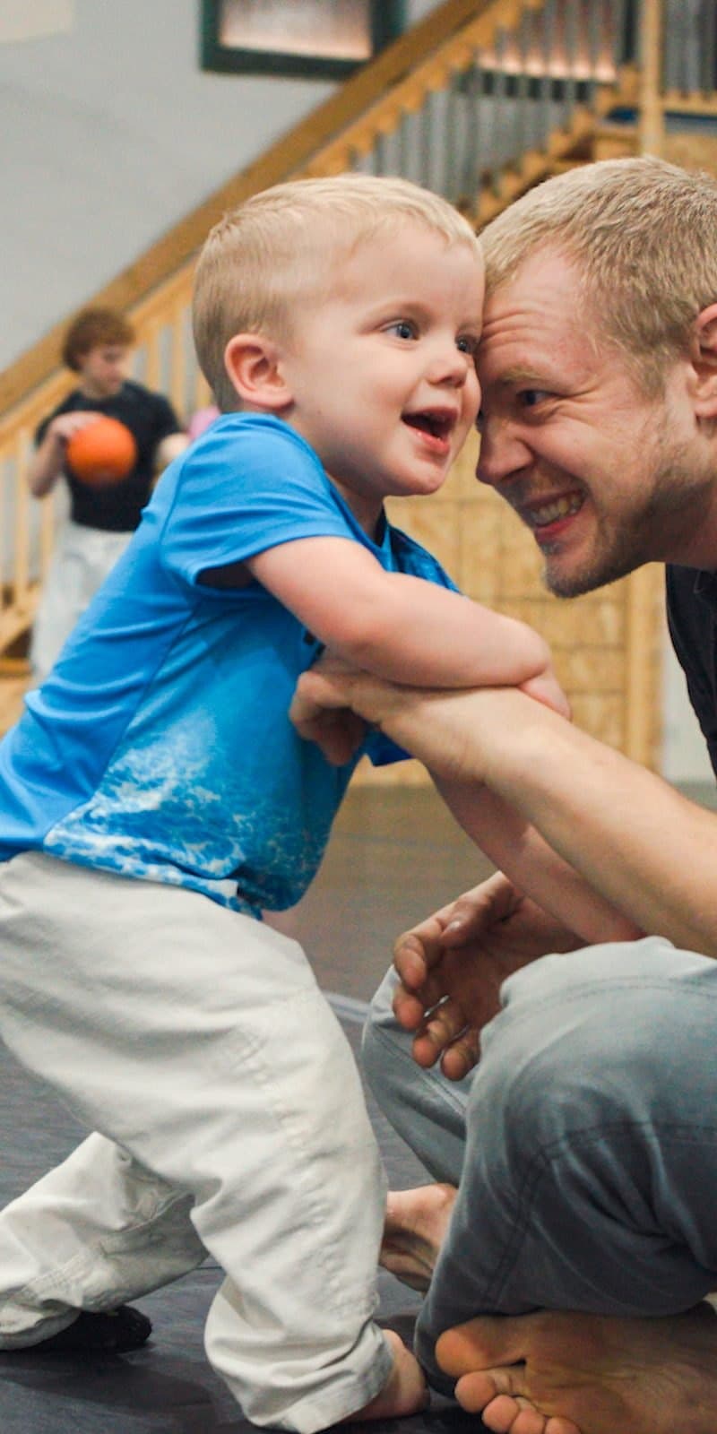 Coach playing with a young child on the mat