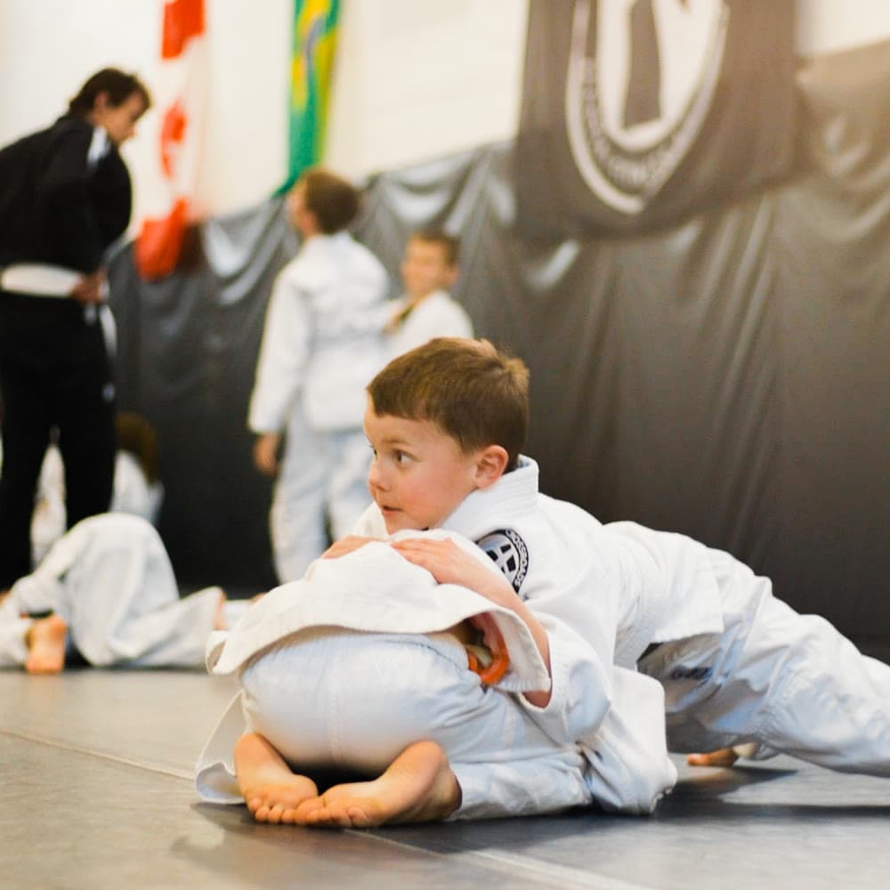 Young student holding guard during a kids Brazilian Jiu-Jitsu class