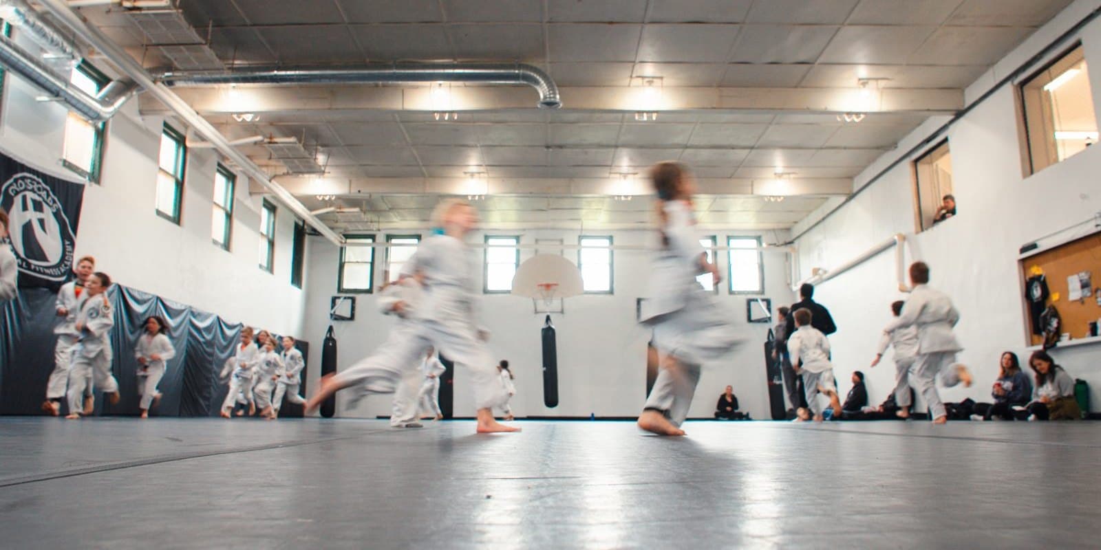 Wide view of the academy training floor with kids moving across the mat