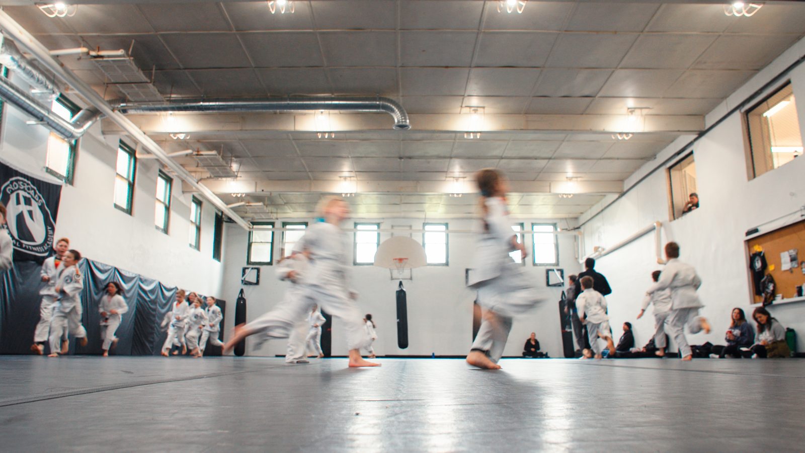 Wide view of the academy training floor with kids moving across the mat