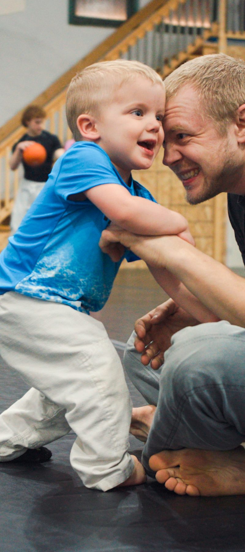 Coach playing with a young child on the mat